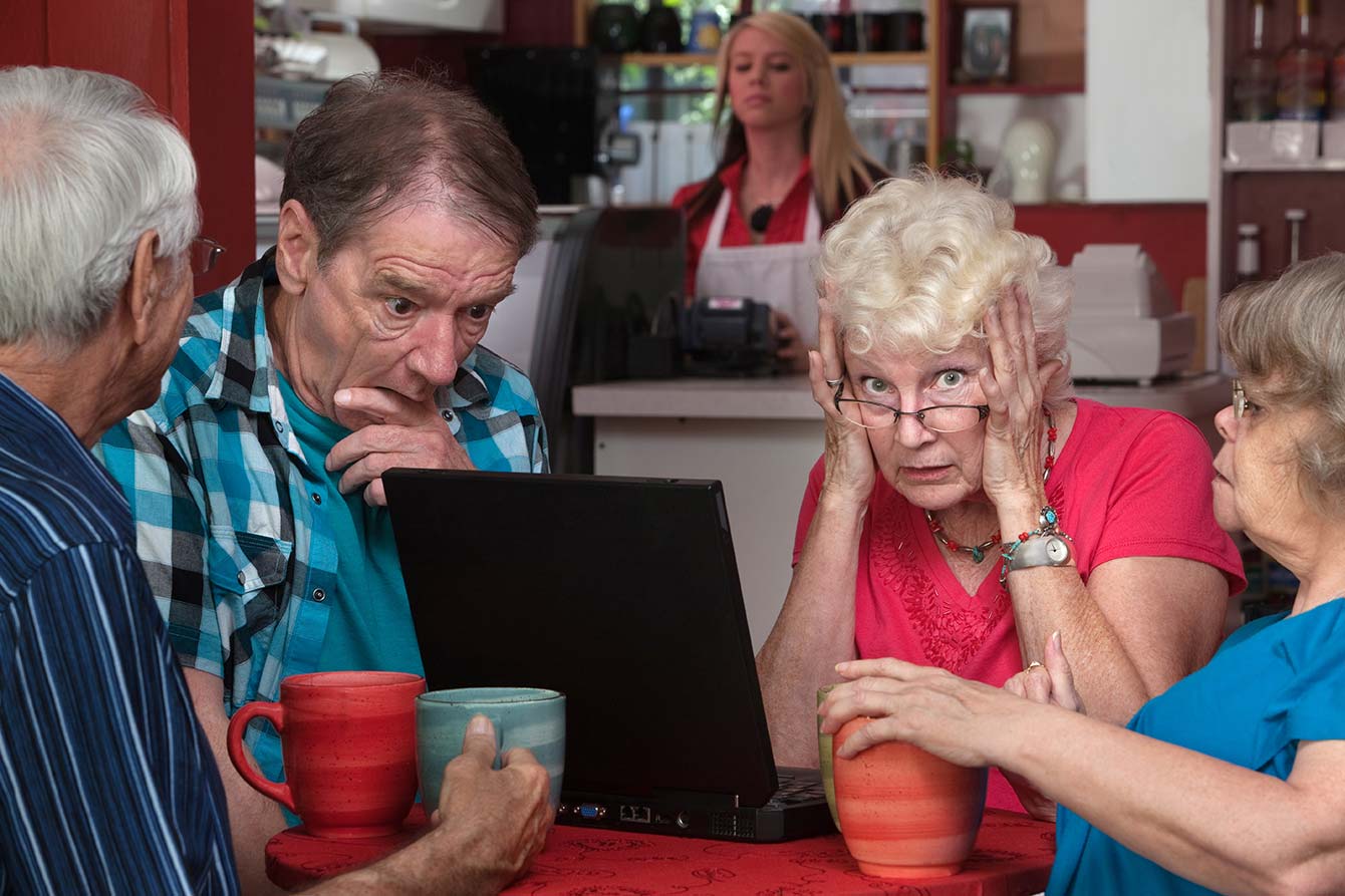 Older lady in a restaurant with a group of friends covering her ears due to loud noise
