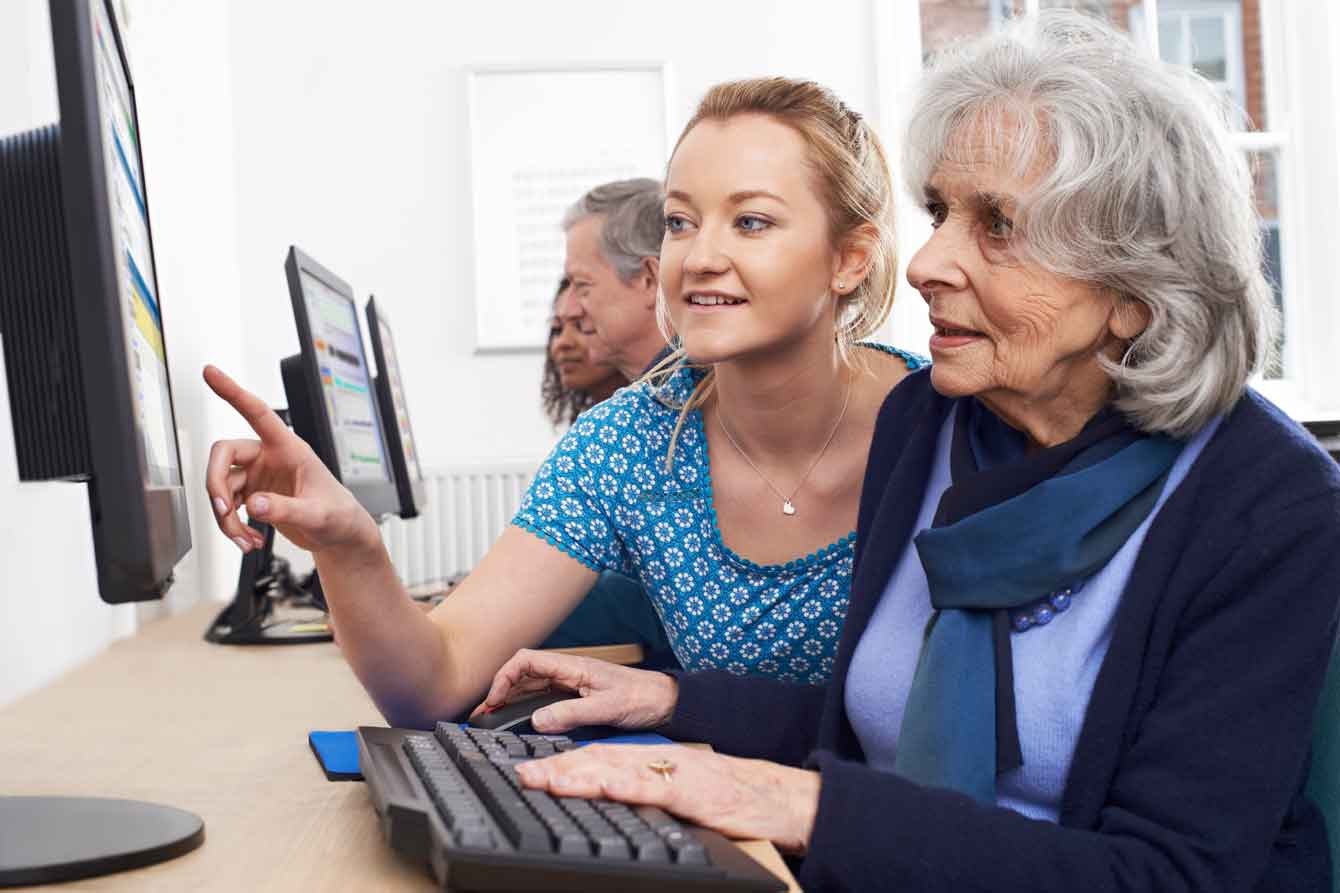 Tutor helping senior woman in a computer class