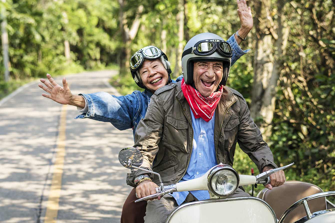 Happy senior couple riding a classic scooter
