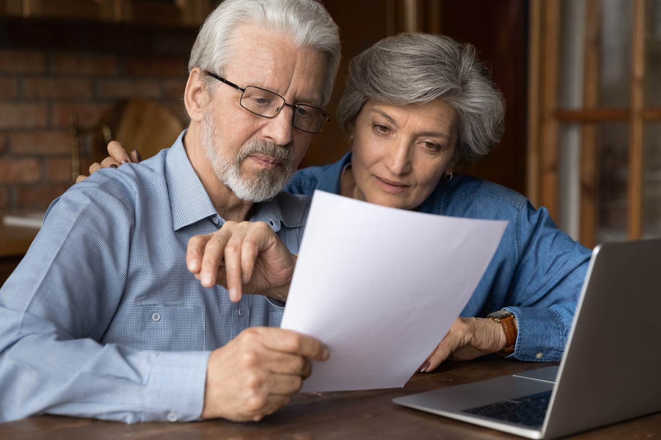 focused senior spouses reading insurance policy terms