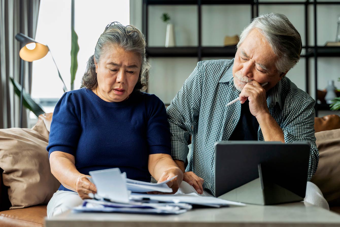 senior couple seriously comparing insurance policies