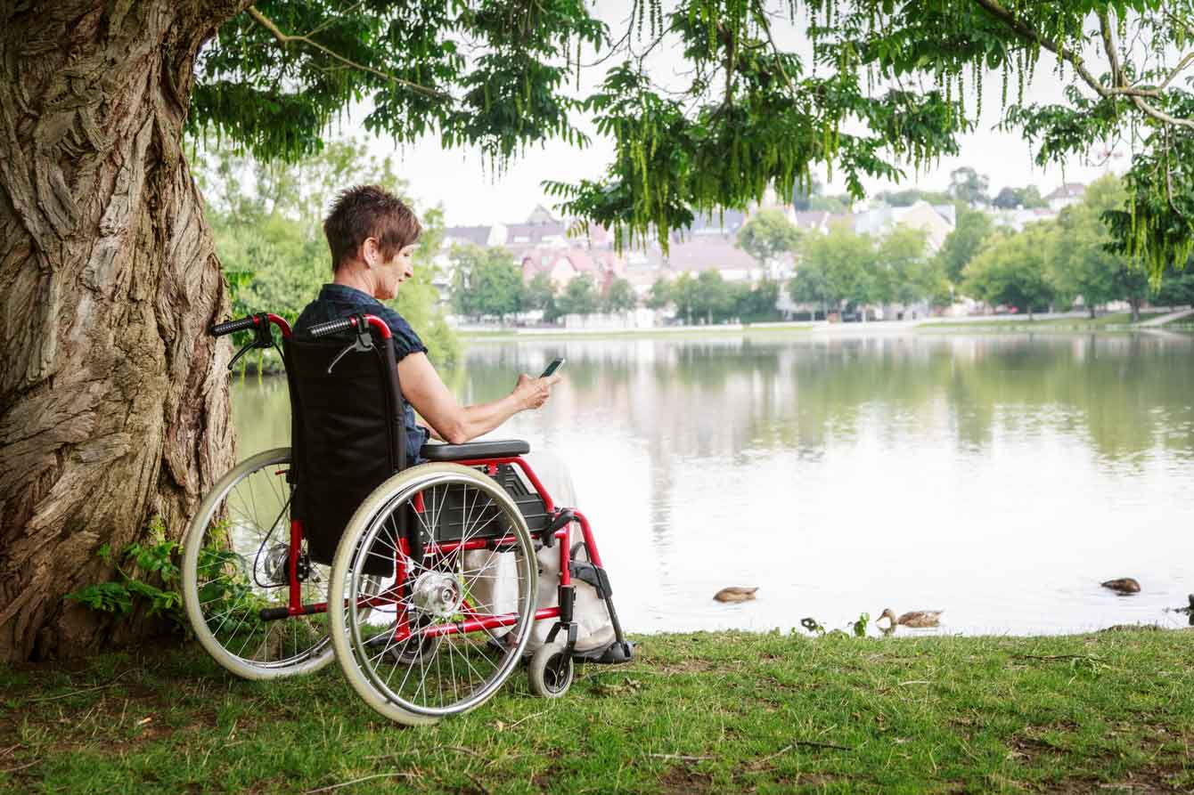 disabled senior woman chatting on the phone by the lake