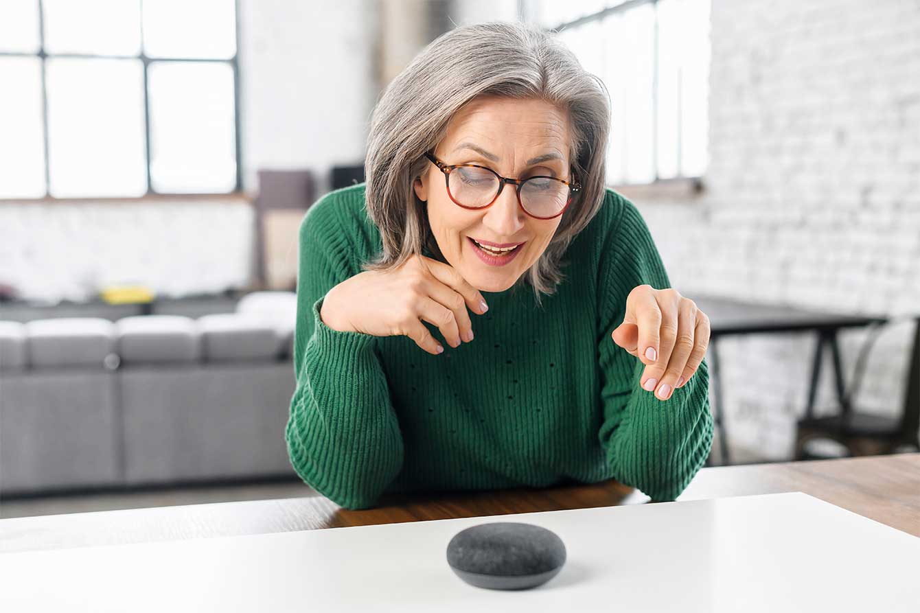 An older woman uses voice commands to instruct a wireless device
