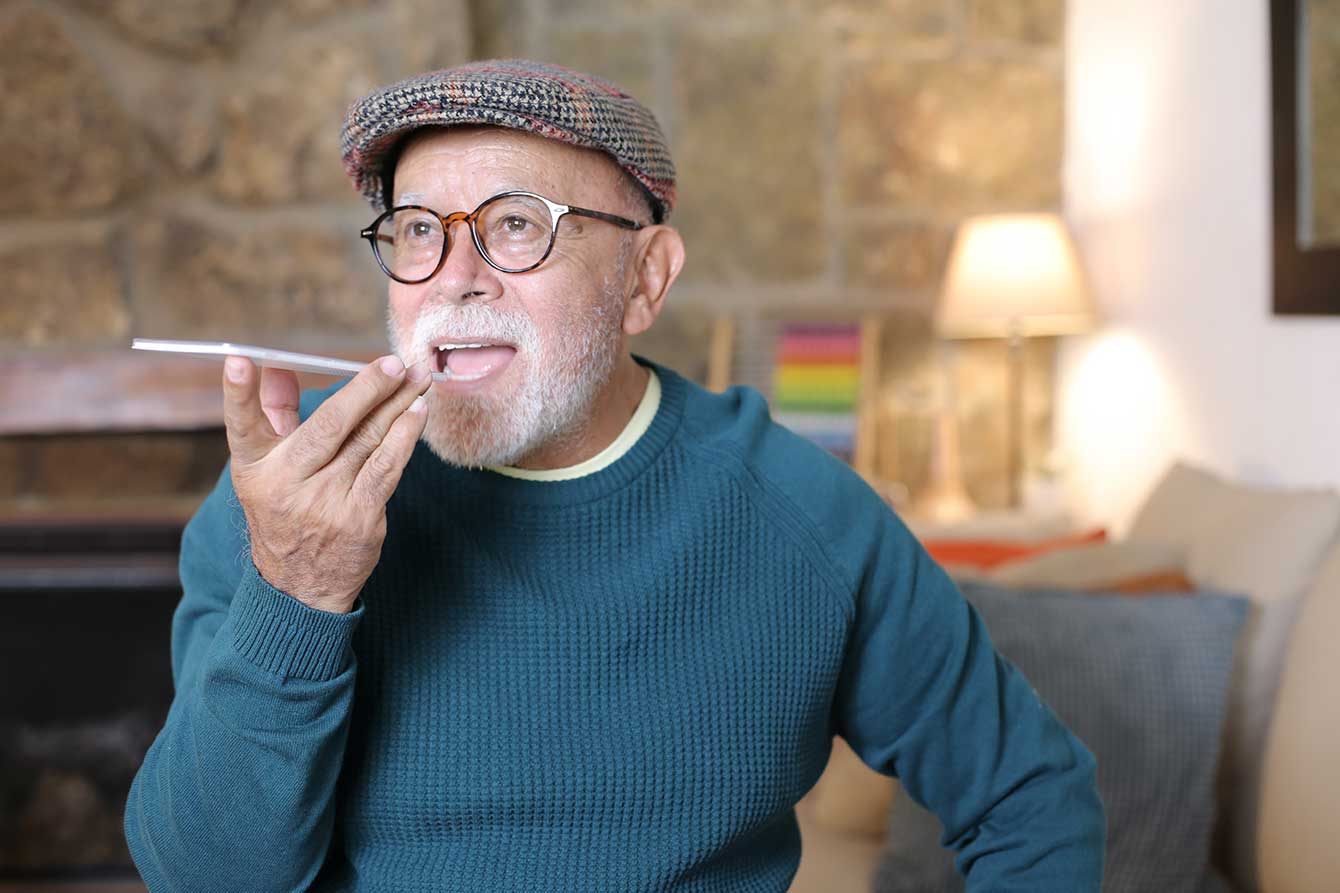An older man gives a voice command to his mobile phone