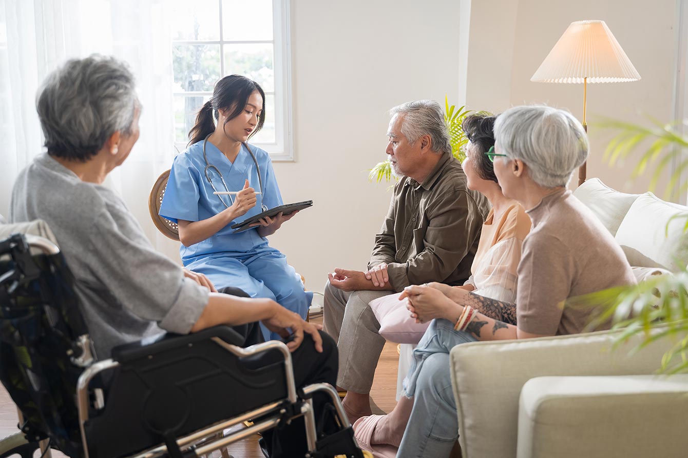 Nurse sitting with group of seniors discussing care