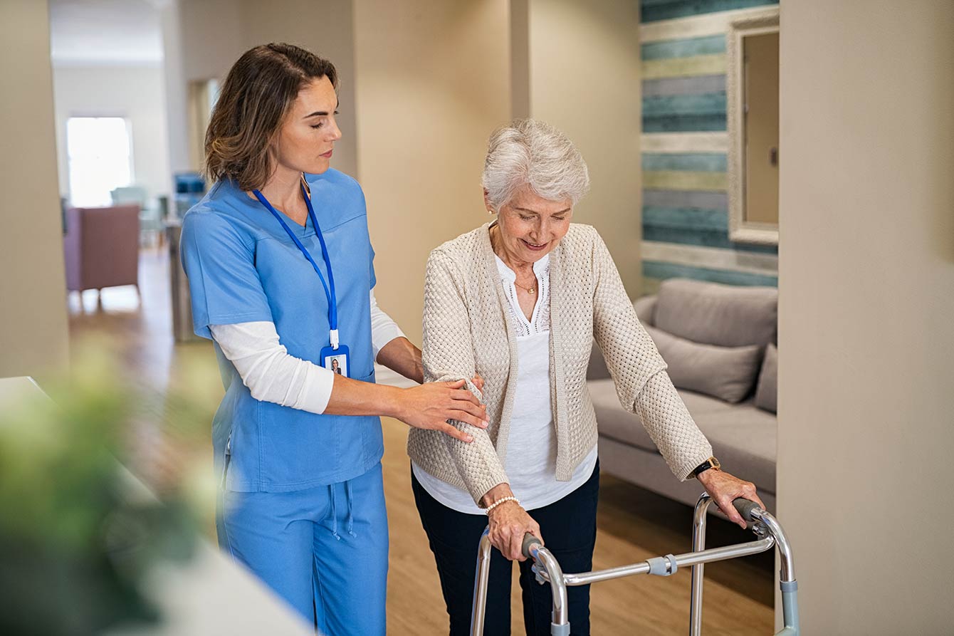 Nurse helping senior using walker
