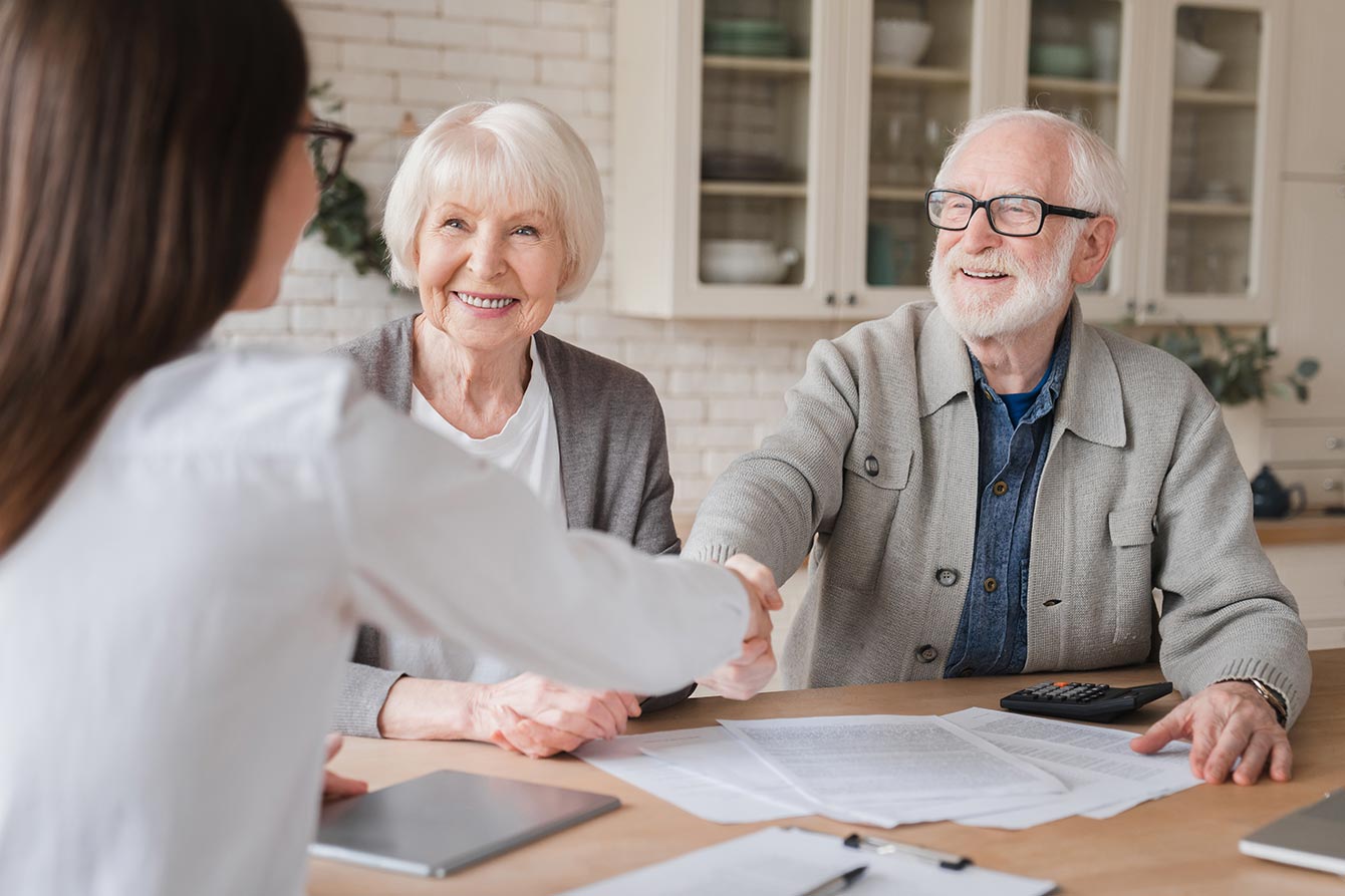 Senior couple with nurse shaking male senior's hand