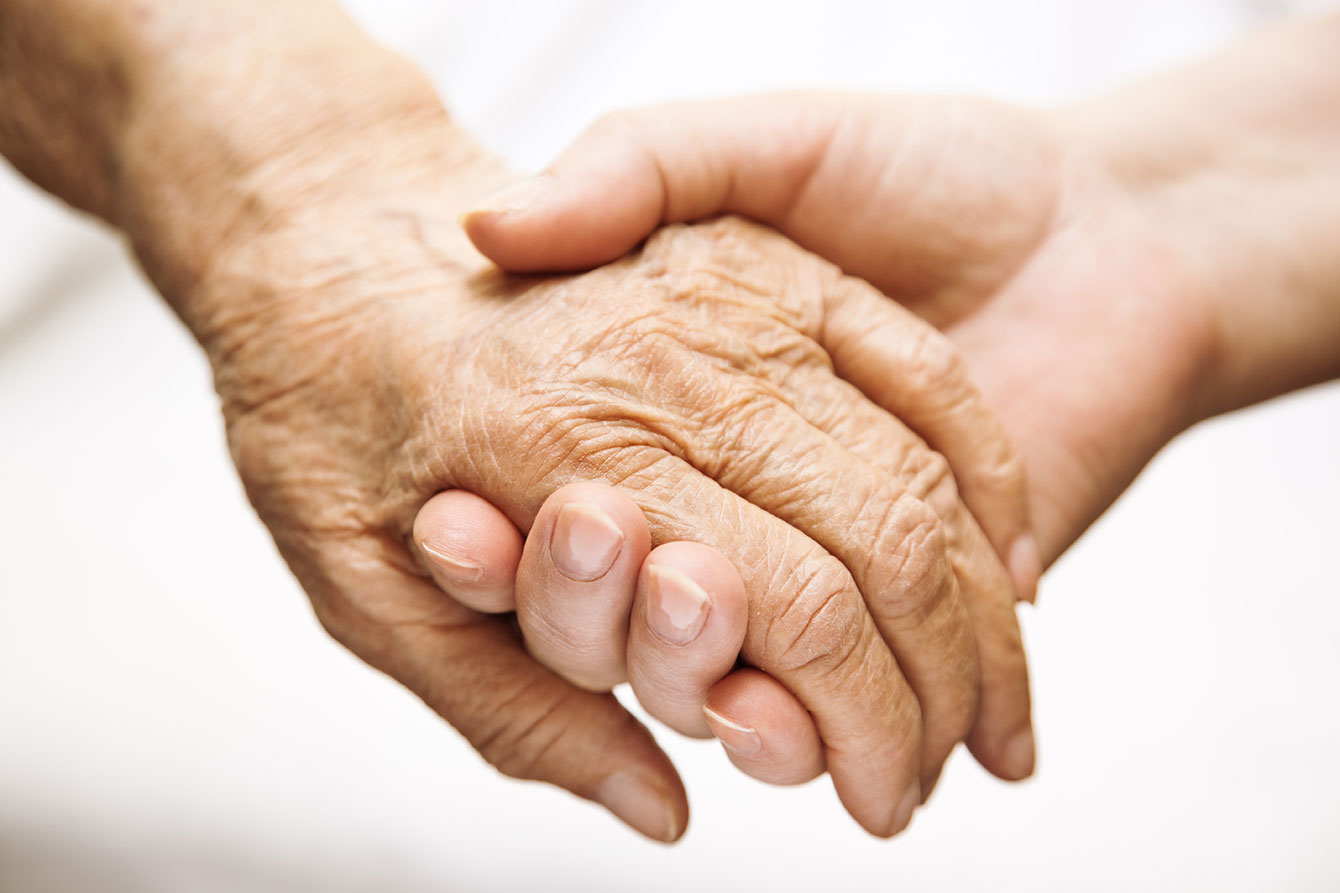 Close-up of a senior female hand holding a younger female hand