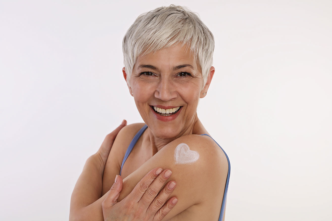 Attractive older woman with suntan lotion in the shape of a heart on her arm