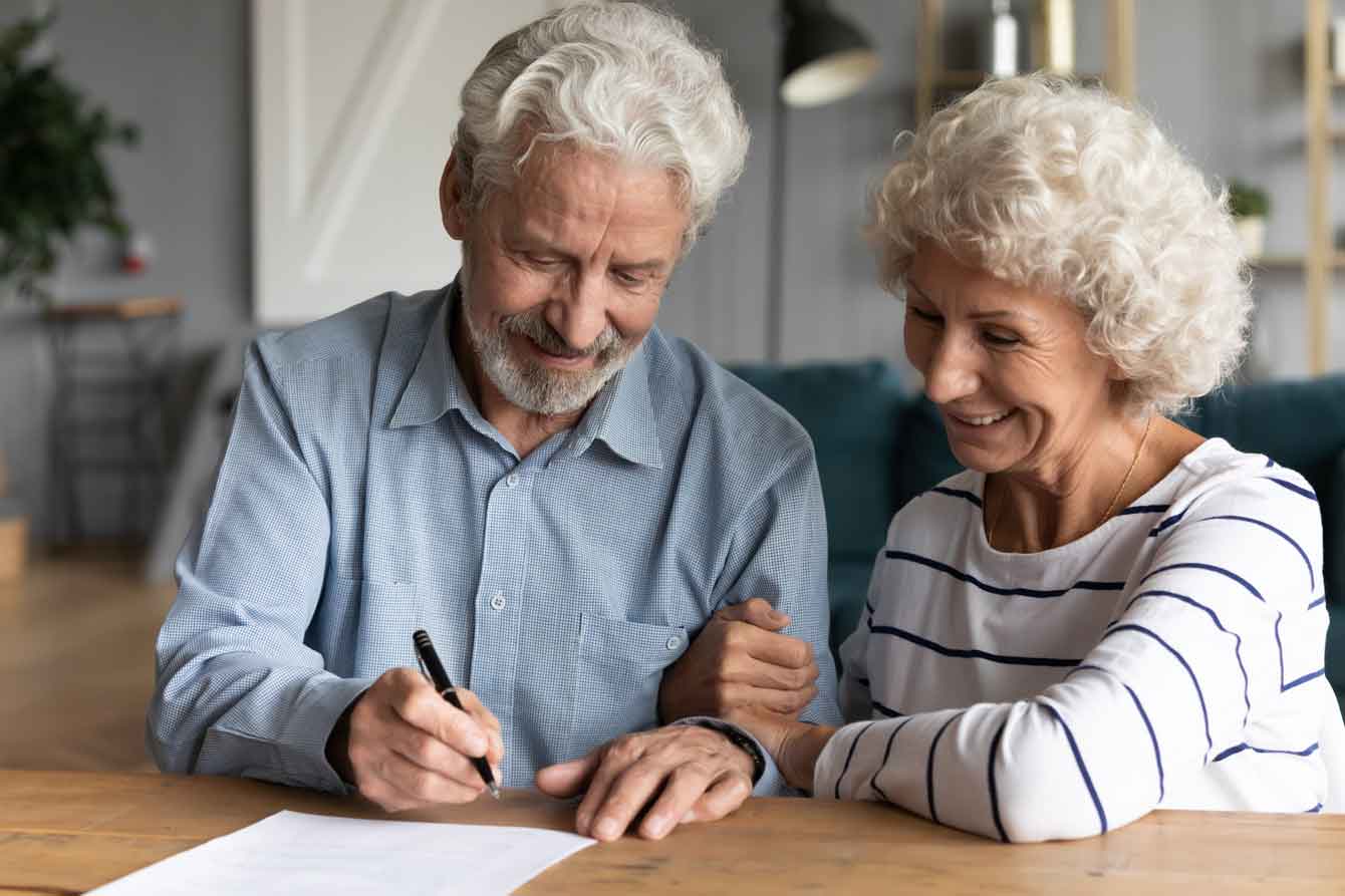 An older couple signs documents