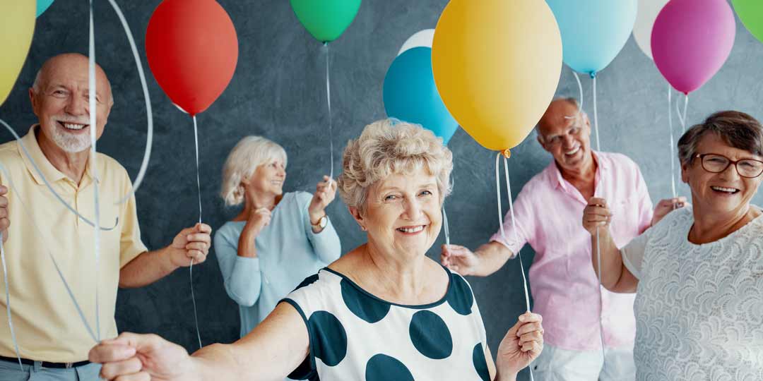 happy senior citizens with balloons