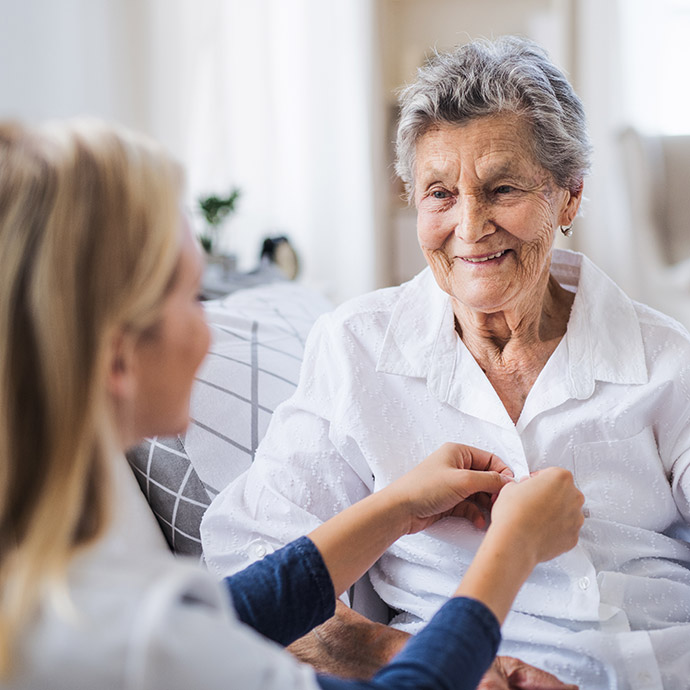 home care worker helping dress smiling senior