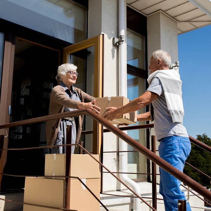senior couple carrying cardboard boxes while moving to new house