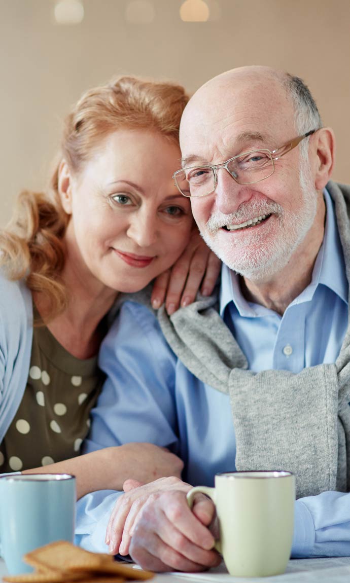 happy senior spouses having tea by table