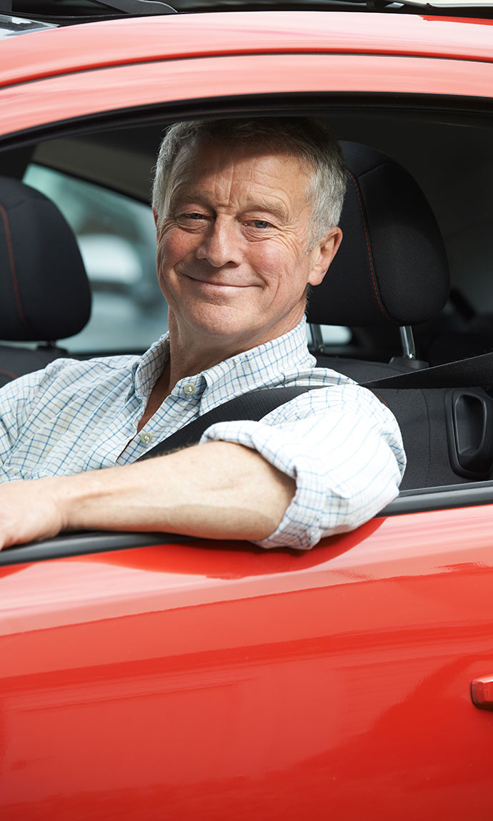 senior man driving red car