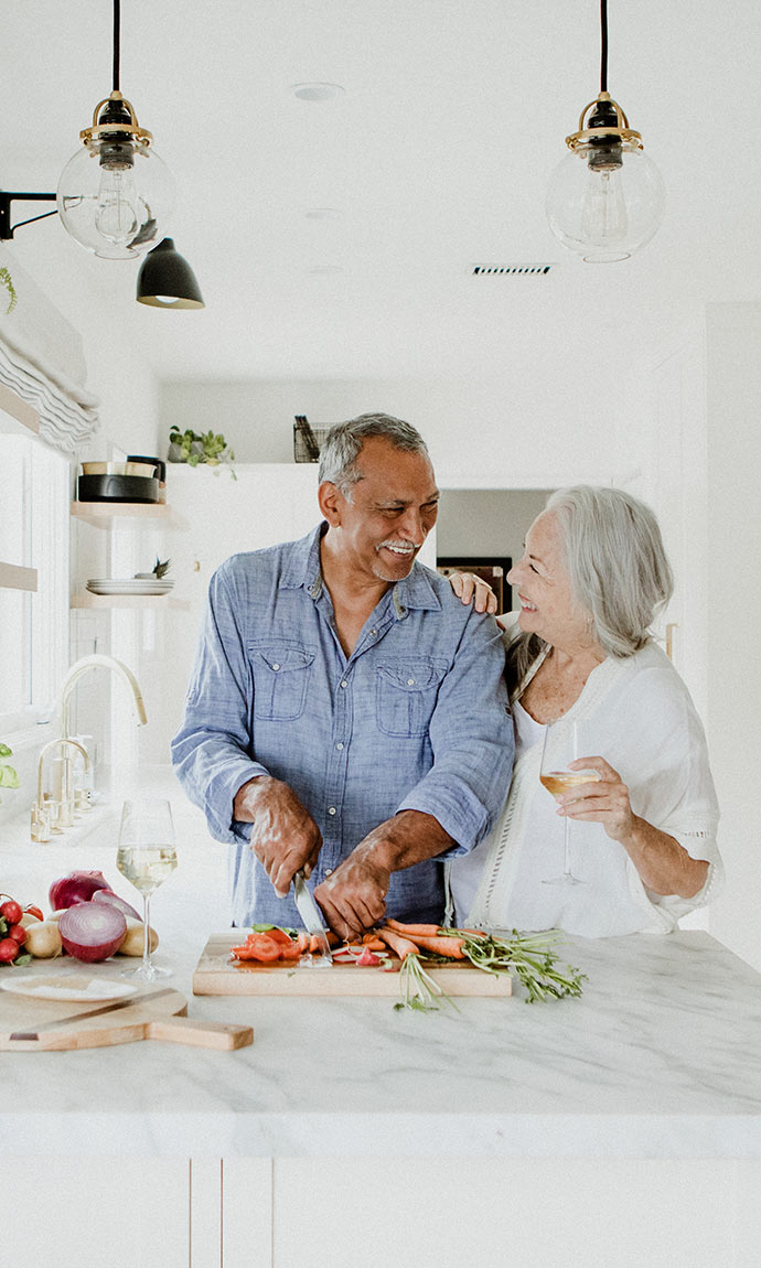 smiling senior couple cutting vegetables