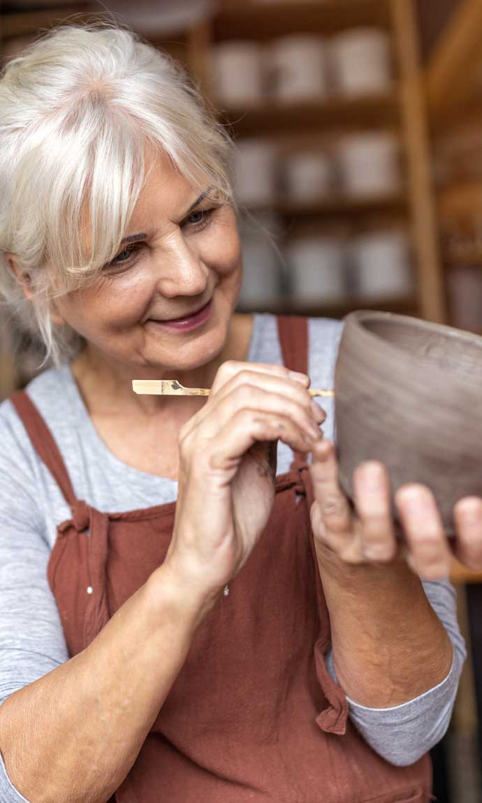 senior lady makes ceramics in pottery class