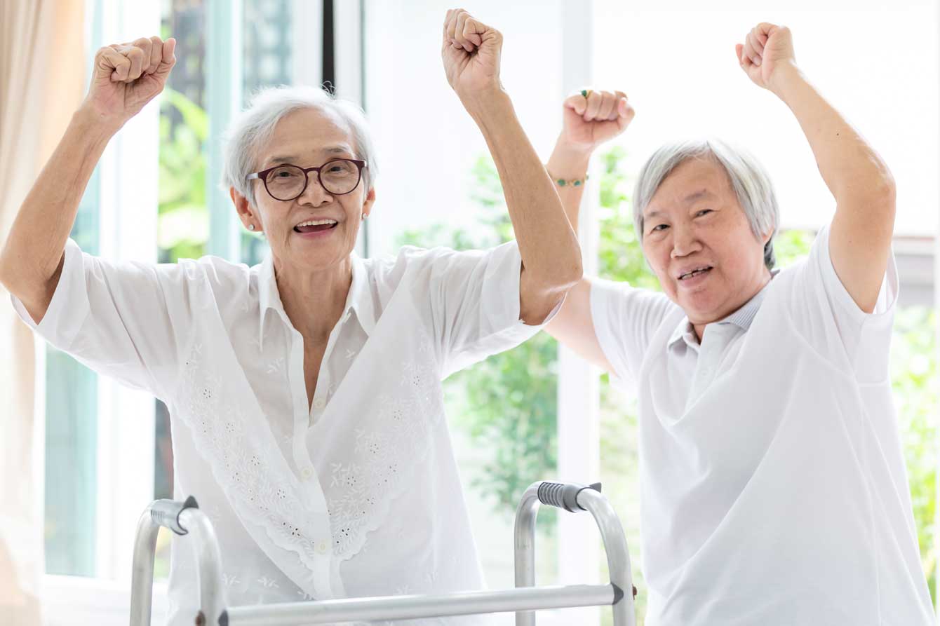 Two old asian ladies raise their hands in victory