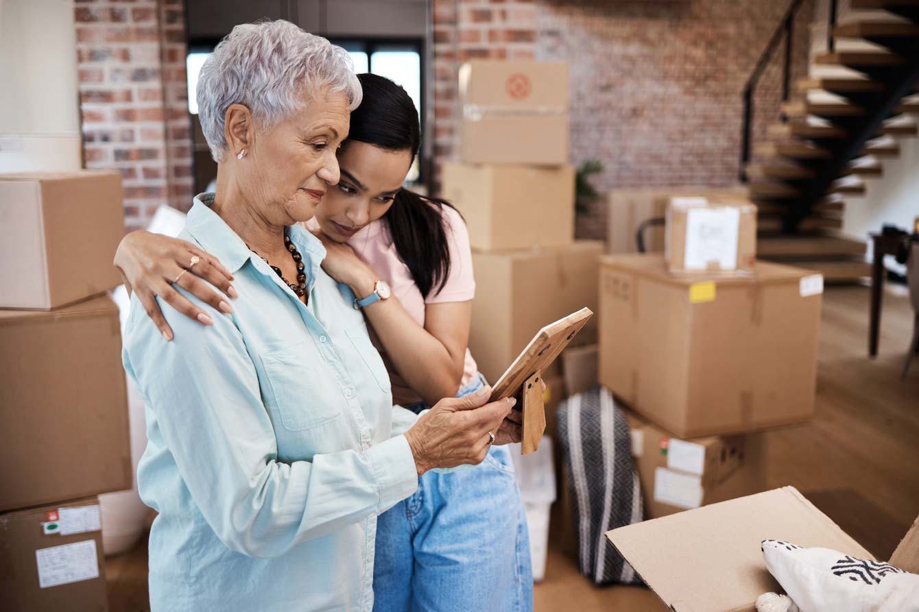 mother and daughter fondly looking at a framed picture while packing for a move