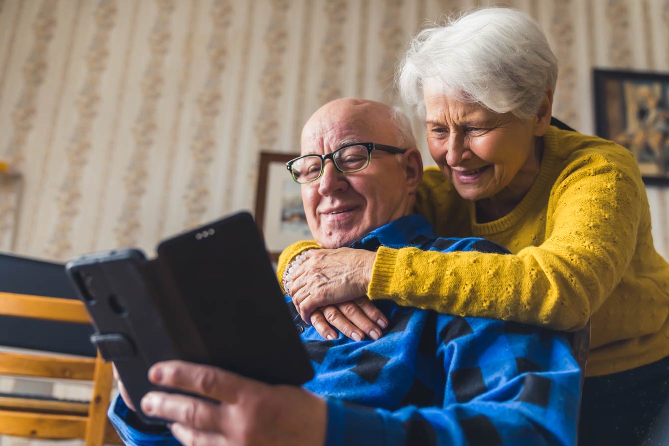 senior couple hugging while on a video call using their phone
