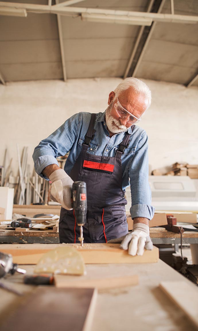 senior carpenter drilling wood